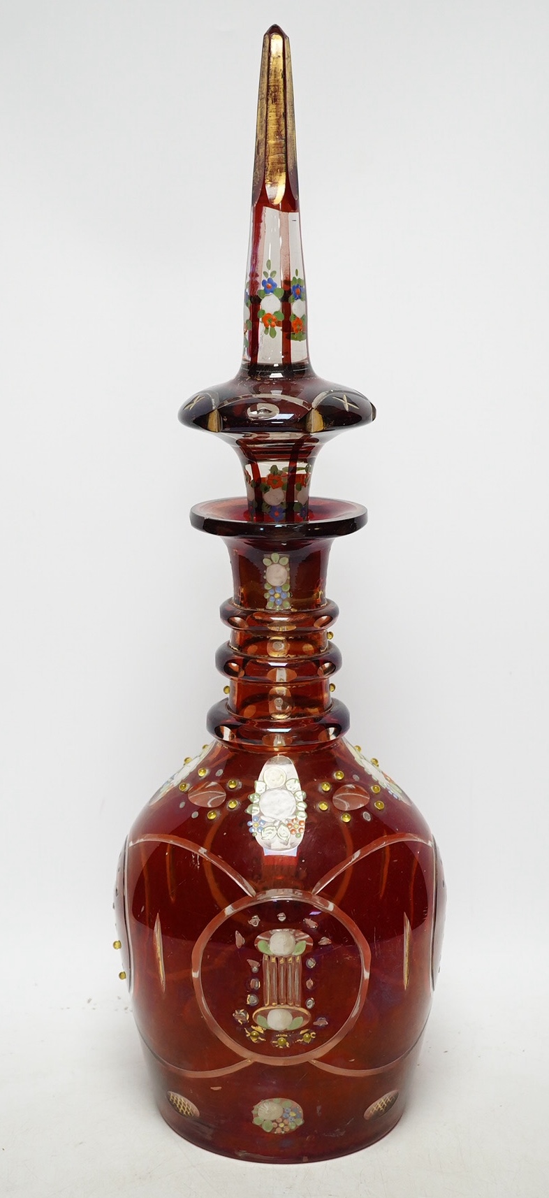 An early 20th century Bohemian overlaid and painted ruby glass decanter, 51cm. Condition - fair